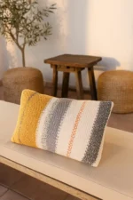 Handgemachter gestrickter Kissenbezug Ege Late Summer Senfgelb Creme Grau verkauft durch Elly Living auf heller Sitzbank im mediterranen Wohnstil