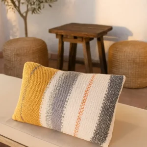 Handgemachter gestrickter Kissenbezug Solea Senfgelb Creme Grau von Elly Living auf heller Sitzbank im mediterranen Wohnstil