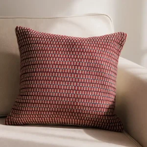 Handgemachter Kissenbezug Riva Rot Creme von Elly Living mit feinem grafischem Muster auf hellem Sessel