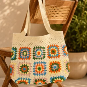 Handgemachte Häkeltasche Mavina Creme Bunt von Elly Living mit buntem Granny-Square-Muster auf Holzstuhl