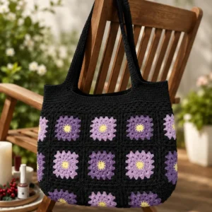 Handgemachte Häkeltasche Viola Schwarz Lila Gelb von Elly Living mit Granny-Square-Muster auf Holzstuhl